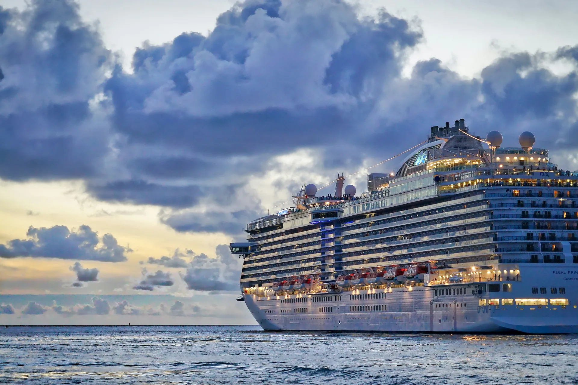 Luxury cruise ship sailing near a coastline at sunrise