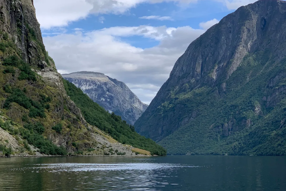 Steep mountains surrounding a calm Norwegian fjord